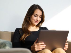 Femeie zâmbind în fața unui laptop